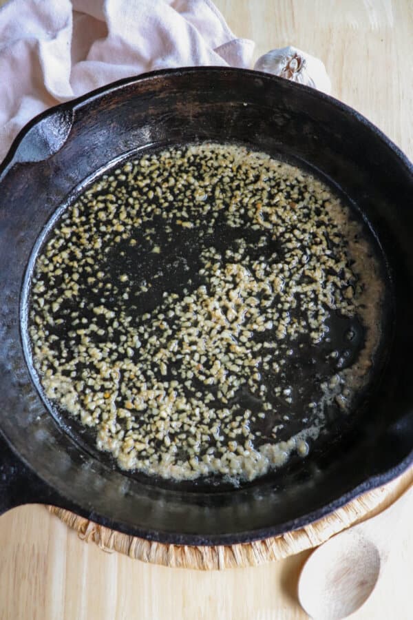 Minced garlic in butter on a cast iron skillet.