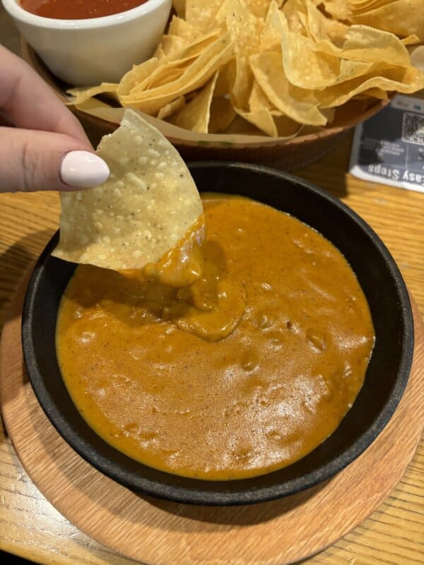 Chili cheese sauce with a chip being dipped in a hand in the Chili's Restaurant.