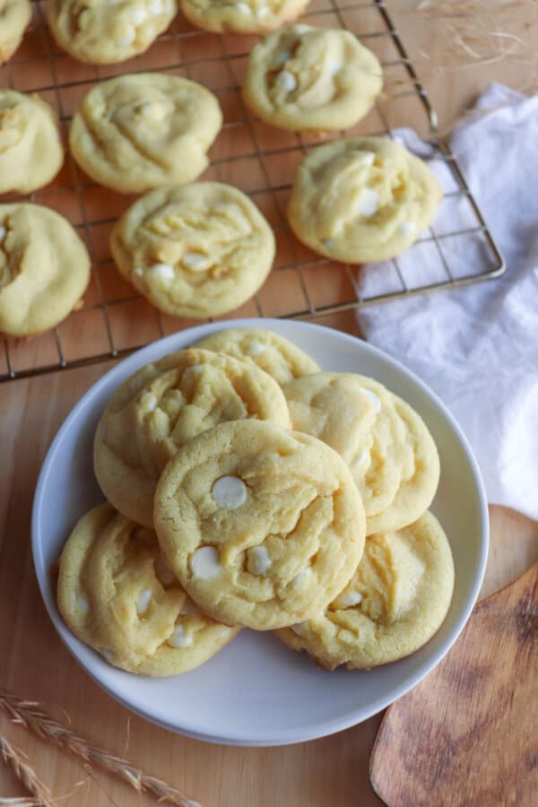 Yellow lemon cookies with white chocolate chips on a white plate.