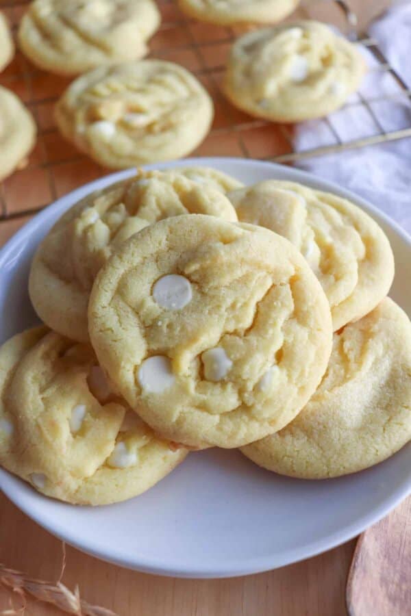 Yellow lemon cookies with white chocolate chips on a white plate.