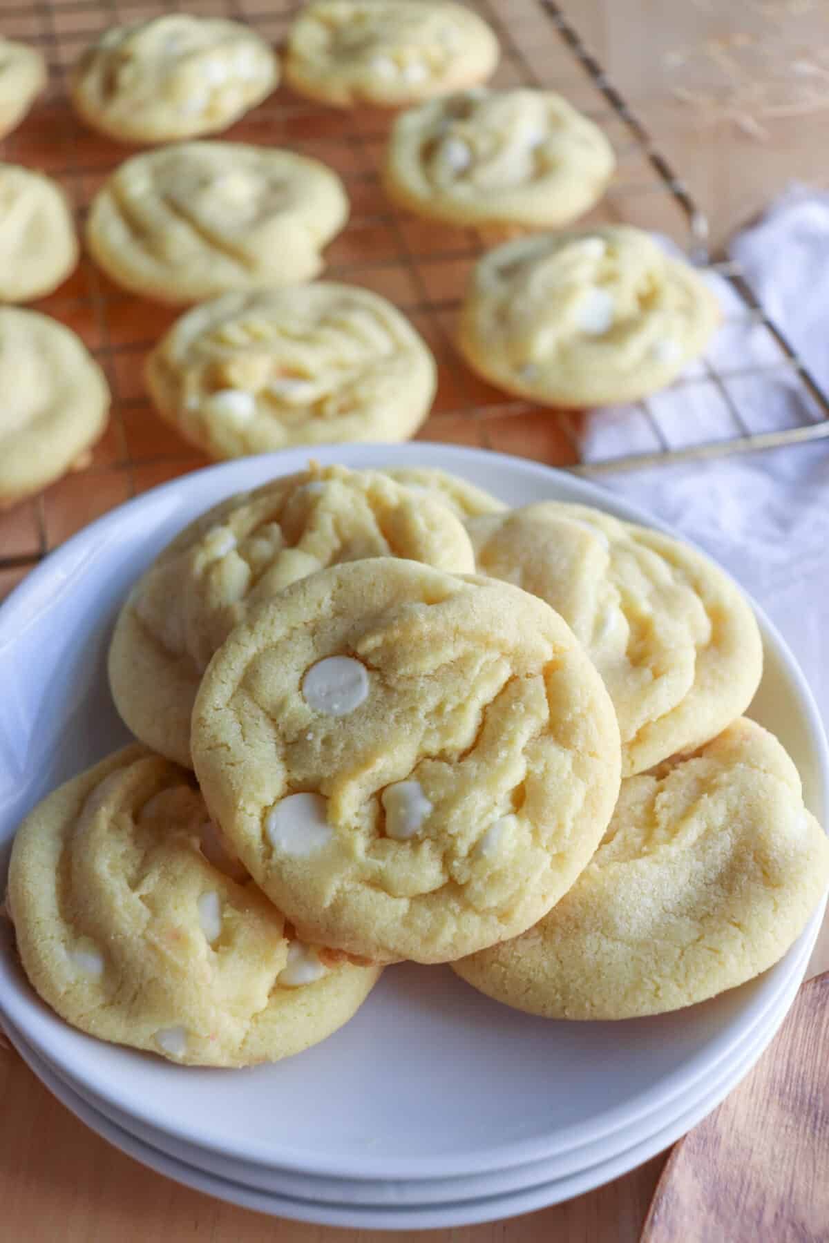 Yellow lemon cookies with white chocolate chips on a white plate.