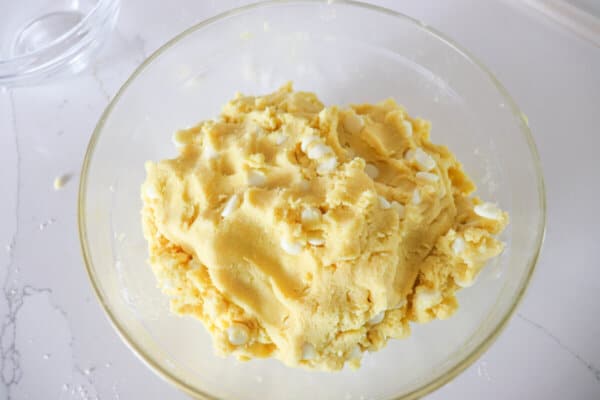 Yellow cookie dough in a clear bowl.