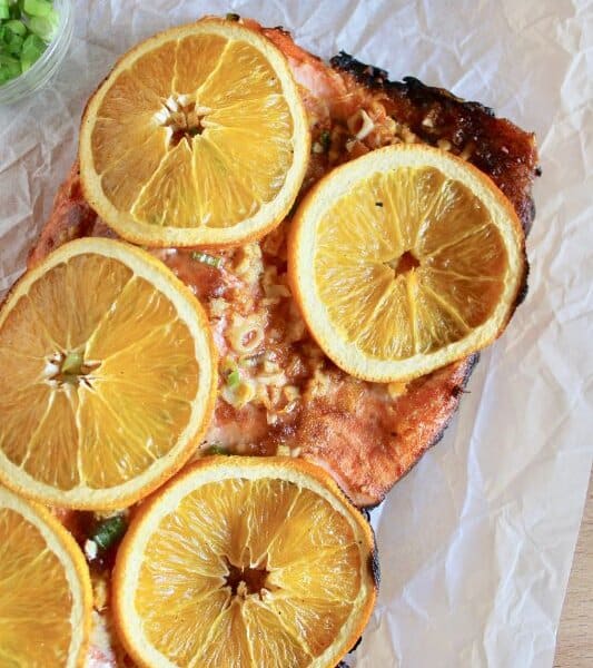 Grilled salmon cooked with orange slices layered on top.
