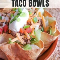 Taco salad topped with shredded cheese, green onion and sour cream in a tortilla bowl.