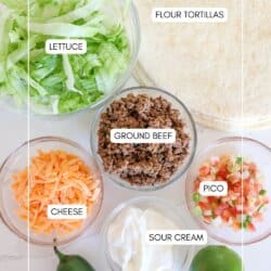 Ingredients for air fryer taco bowls in clear glass bowls on a white counter.