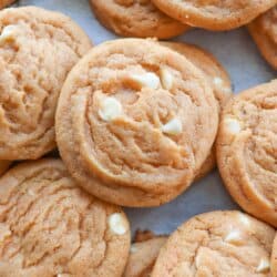 Baked butterscotch cookies with white chocolate chips on a parchment lined baking sheet.
