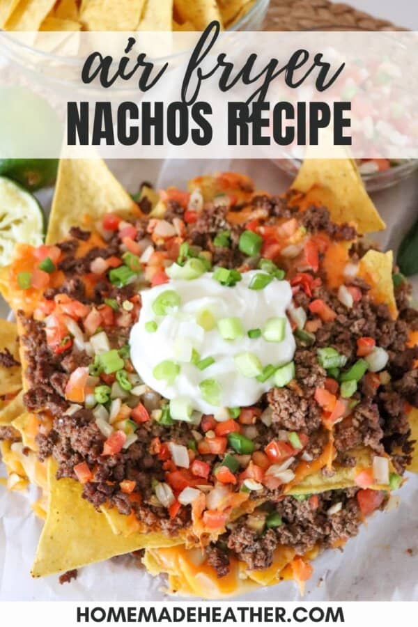 Nachos piled high with ground beef, pico and melted cheese on parchment paper.