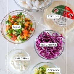 Shrimp Taco Ingredients in clear glass bowls on a white counter.