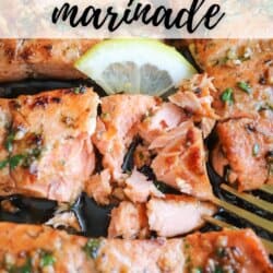 Salmon fillets in a cast iron skillet topped with fresh parsley and lemon slices.