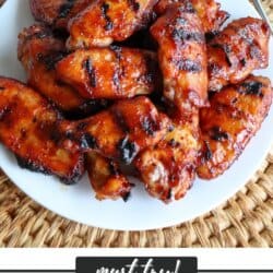 BBQ chicken wings with grill lines on a white plate.