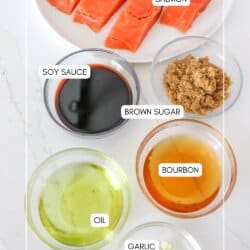 Ingredients for bourbon salmon in clear glass bowls on a white counter.