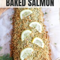 Salmon fillet covered in a crust of panko and herbs on a sheet of parchment paper topped with lemon slices for garnish.