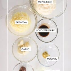 Caesar salad dressing ingredients in clear glass bowls on a white surface.