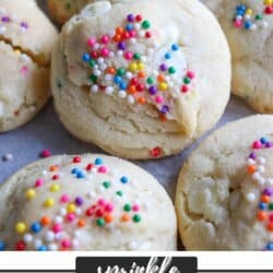 Vanilla pudding cookies topped with colorful sprinkles on a parchment paper lined baking sheet.