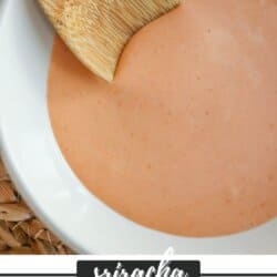 Spicy mayo sauce in a white bowl with a wooden spoon dipped in on the left.