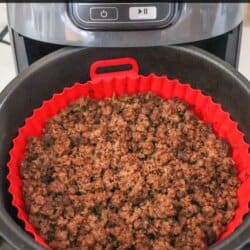 Ground beef seasoned with taco spices and cooked in the basket of an air fryer with a red liner.