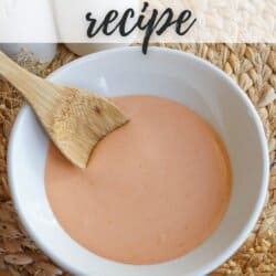Spicy mayo sauce in a white bowl with a wooden spoon dipped in on the left.