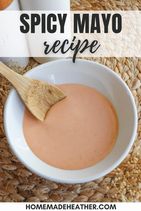 Spicy mayo sauce in a white bowl with a wooden spoon dipped in on the left.