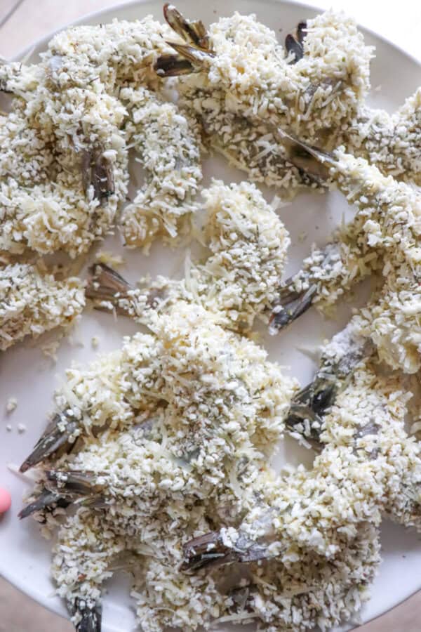 Raw Panko breaded shrimp on a white plate.