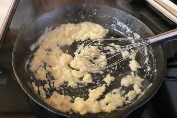 Skillet with a rue of flour and butter with a whisk in it.
