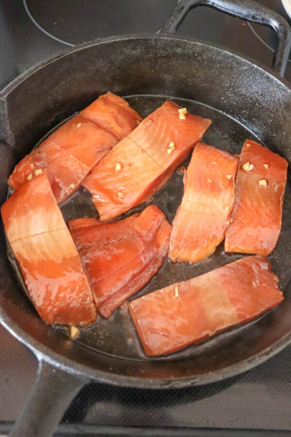 Two inch salmon fillets in a cast iron skillet.