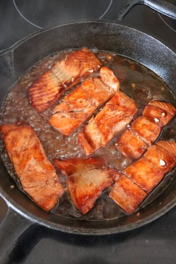 Salmon fillets covered in a brown sugar & bourbon glaze in a cast iron skillet.