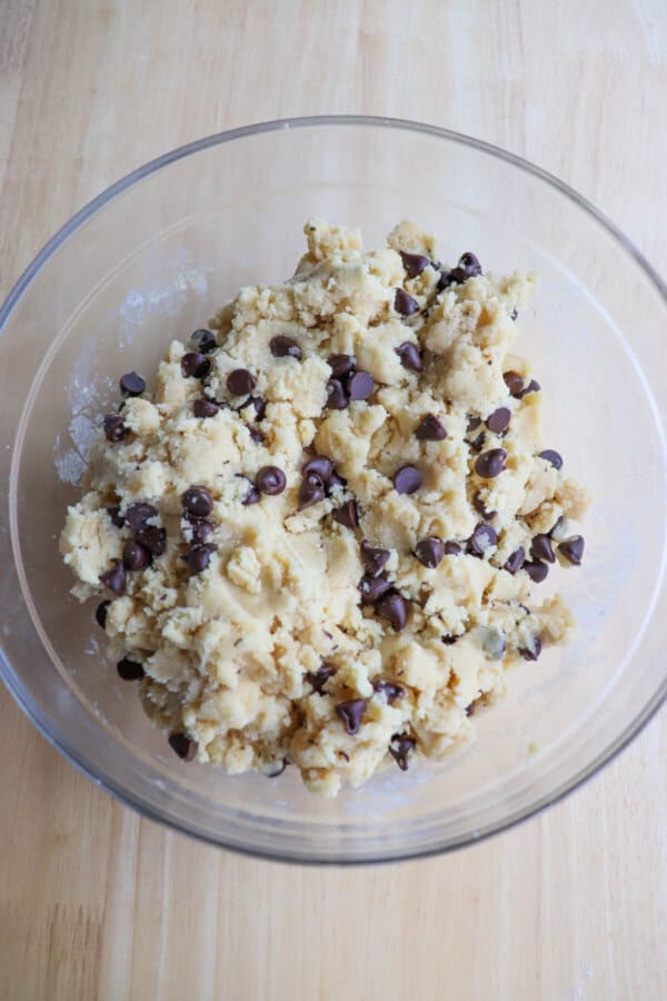Chocolate chip cookie dough in a medium clear glass bowl.