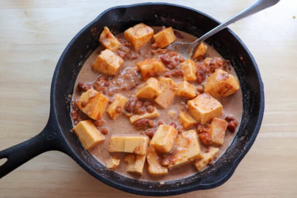 Queso ingredients of chili and cubed Velveeta mixed in a cast iron skillet.