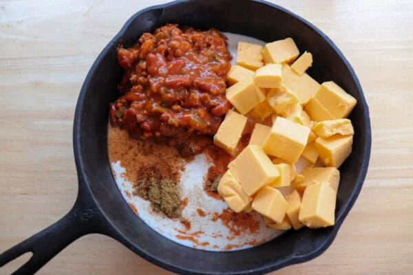 Ingredients for queso skillet dip in a cast iron skillet.