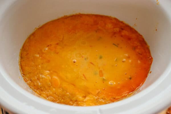 Beer cheese melted in a small white crockpot.