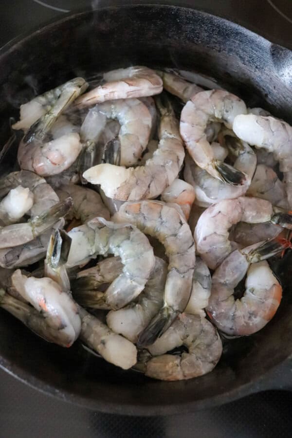Raw shrimp in a cast iron skillet.