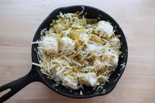 Cubed cream cheese, shredded pepper jack cheese and diced chilis mixed in a cast iron skillet.