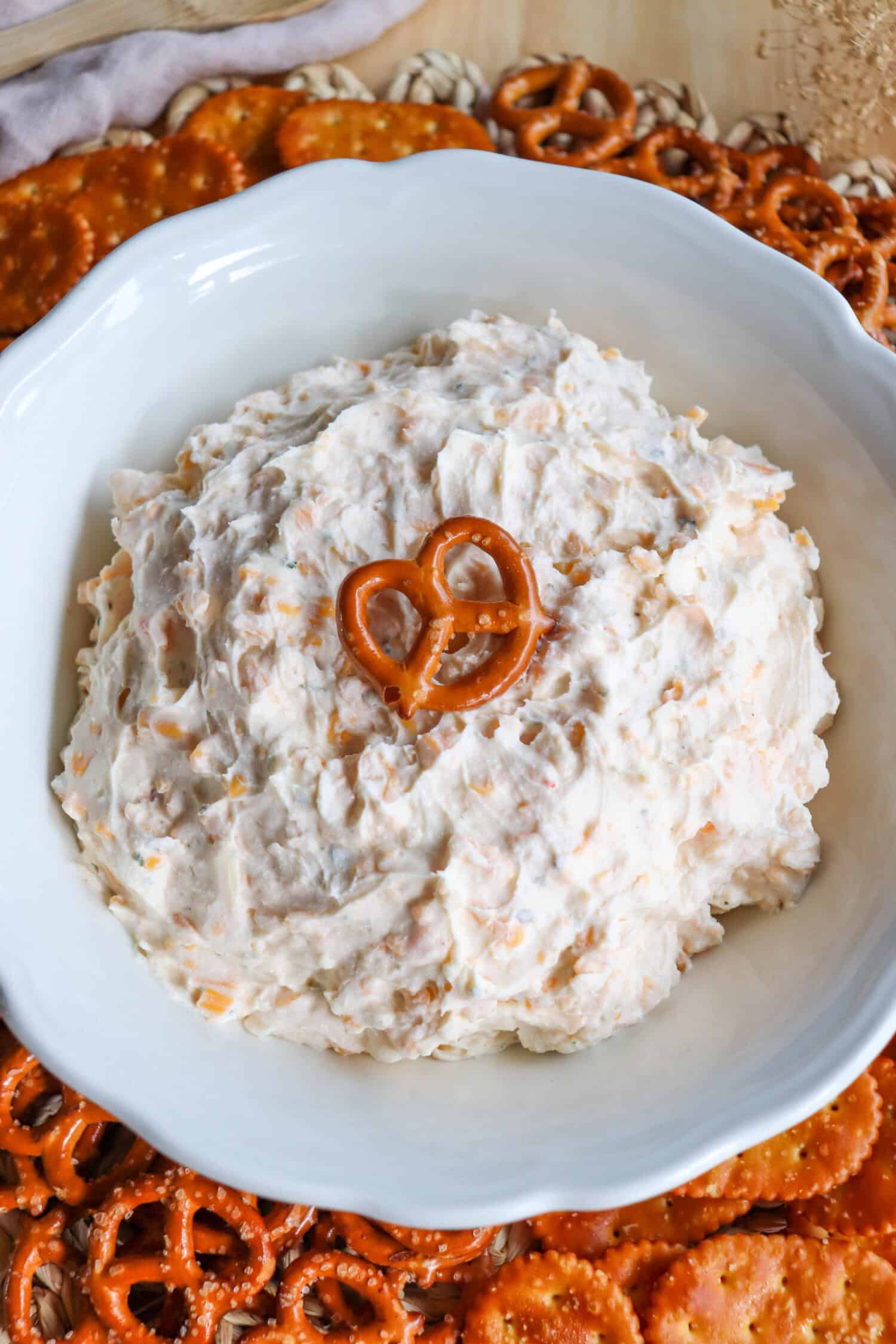 Creamy ranch beer cheese dip in a white bowl, surrounded by pretzels and crackers with a pretzel on top.