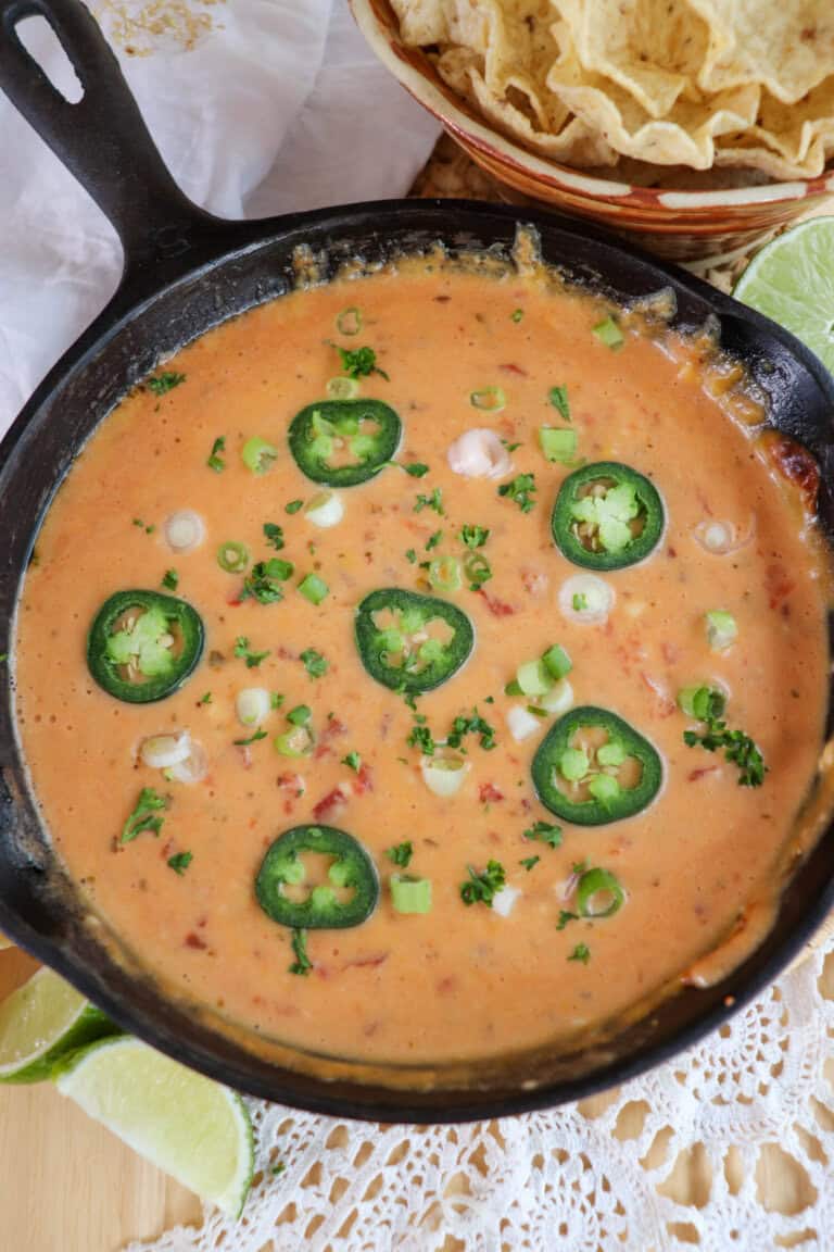 Cheesy rotel dip with no meat in a cast iron skillet topped with sliced jalapenos and diced green onions.
