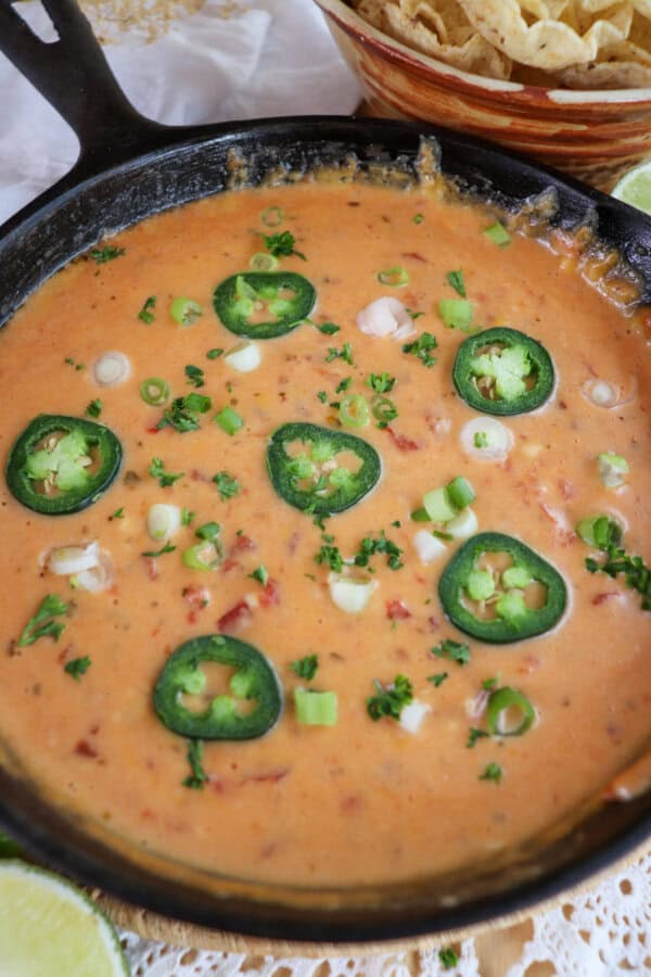 Cheesy rotel dip with no meat in a cast iron skillet topped with sliced jalapenos and diced green onions.