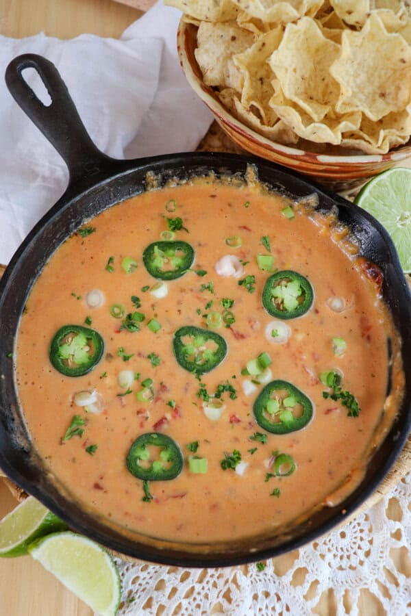 Cheesy rotel dip with no meat in a cast iron skillet topped with sliced jalapenos and diced green onions.