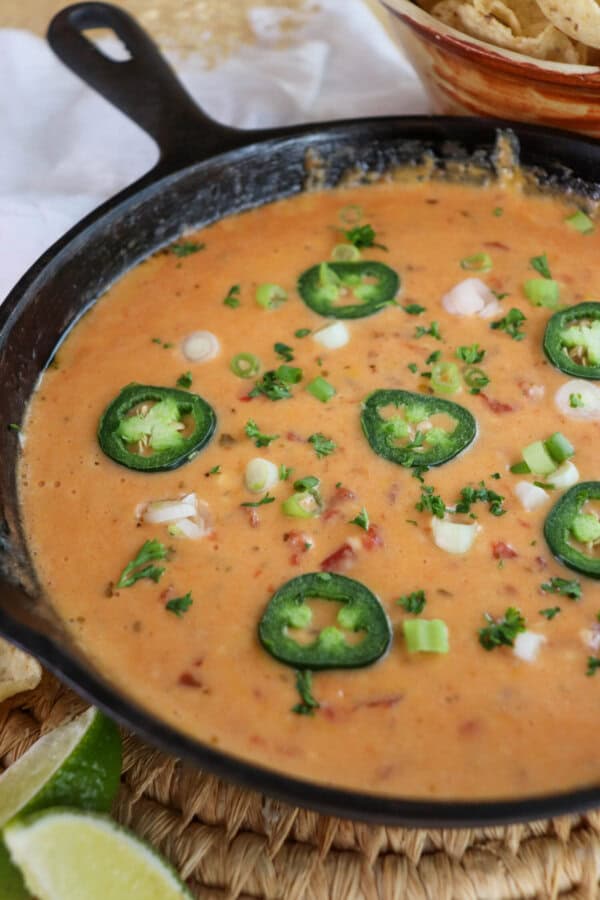 Cheesy rotel dip with no meat in a cast iron skillet topped with sliced jalapenos and diced green onions.