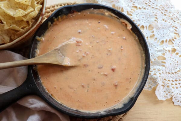 Meatless Rotel dip ingredients stirred together in a five inch cast iron skillet creating a cheesy sauce.