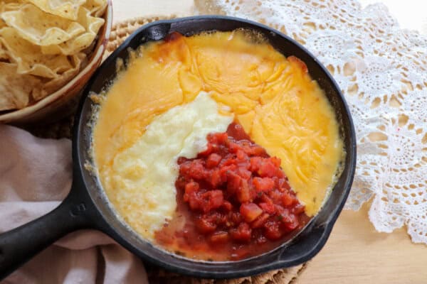 Rotel dip ingredients melting in a cast iron skillet.