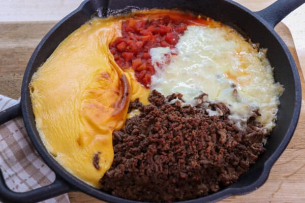 Rotel dip ingredients melted in a large cast iron skillet.
