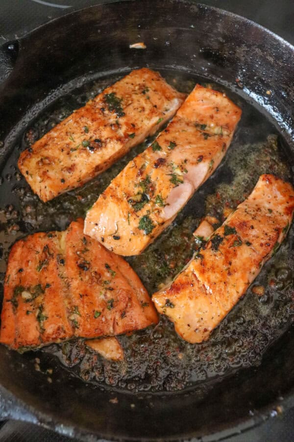 Cooked salmon filets in a cast iron skillet.