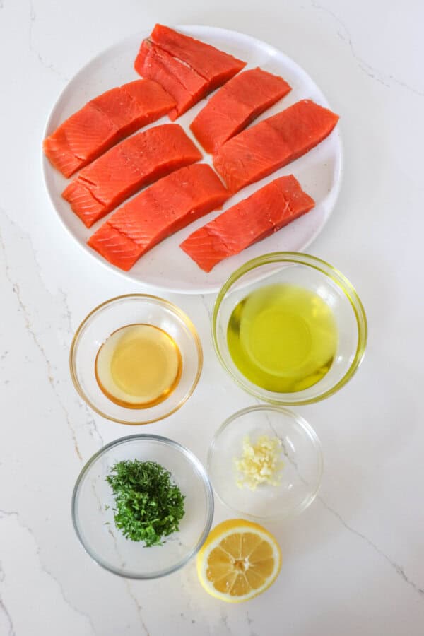 Lemon Salmon marinade ingredients in clear glass bowls on a white counter.