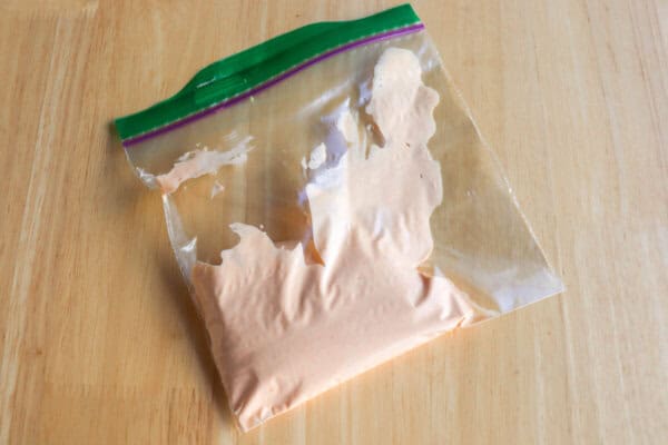 Spicy mayo in a small freezer bag on a wooden table.