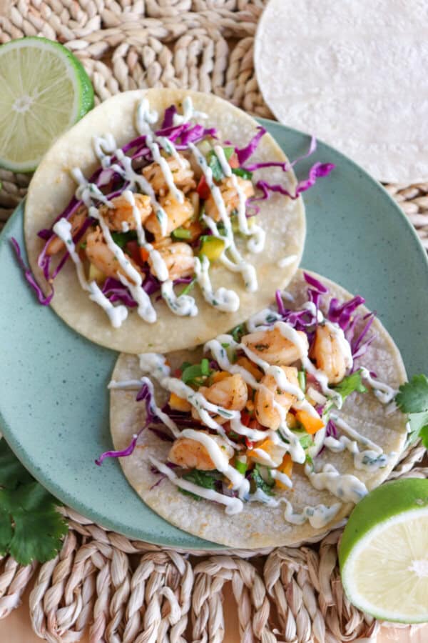 White corn tortilla with shredded red cabbage, fresh salsa and grilled shrimp garnished with a drizzle of cilantro lime crema.