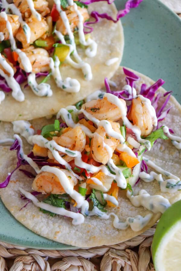White corn tortilla with shredded red cabbage, fresh salsa and grilled shrimp garnished with a drizzle of cilantro lime crema.