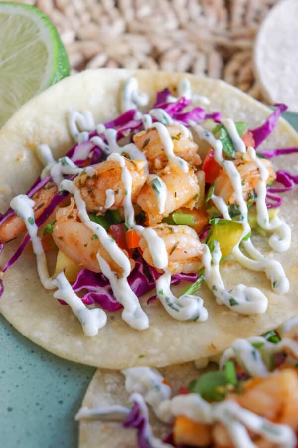 White corn tortilla with shredded red cabbage, fresh salsa and grilled shrimp garnished with a drizzle of cilantro lime crema.