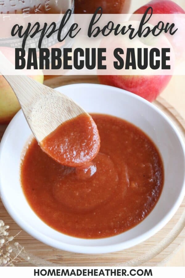 Apple bourbon BBQ sauce in a small white bowl with a wooden spoon dipping into it.