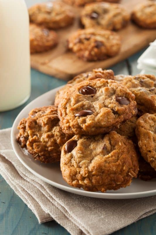 Oatmeal chocolate chip cookies stacked on a white plate.