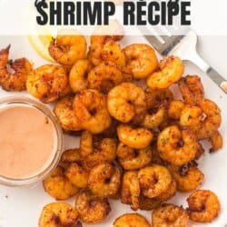 Seasoned shrimp on a white surface with a bowl of spicy mayo.