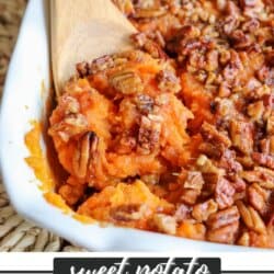 Sweet potato casserole topped with a caramel pecan streusel in a white casserole dish with a wooden spoon scooping out some of the mixture.